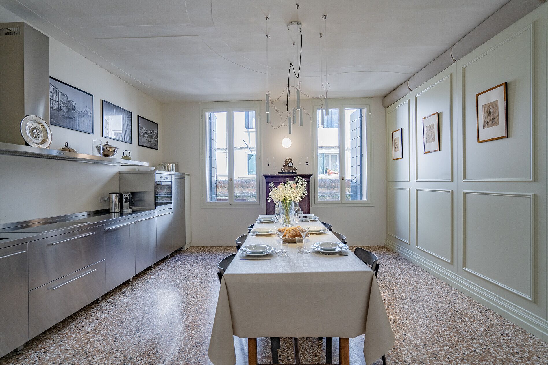 Un comedor con una mesa dispuesta para cuatro, una cocina con electrodomésticos modernos y un amplio ventanal que proporciona luz natural.