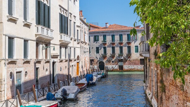 Un canal étroit, bordé de bâtiments historiques dotés de balcons, et un bateau amarré au bord du canal.
