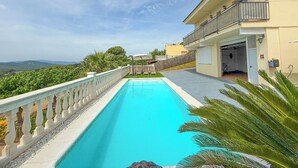 A swimming pool with a white balustrade, a covered patio area, and a view of the surrounding landscape. - Club Villamar - Holiday villa with a beautiful appearance, located at the Spanish Costa Brava. (Lloret de Mar)