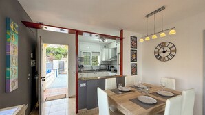 A modern kitchen with white cabinets, a wooden island, and a dining area with a wooden table and white chairs. - Club Villamar - Holiday villa with a beautiful appearance, located at the Spanish Costa Brava. (Lloret de Mar)