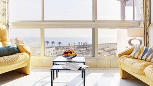 Un salon moderne doté d’une grande fenêtre, de deux canapés en cuir jaune, d’une petite table sur laquelle se trouve un panier de fruits et d’une lampe.