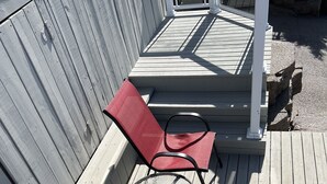 A wooden deck with two red chairs and a glass table. - Stunning 1-Bedroom Furnished Apartment Overlooking Beautiful Halifax Harbour (Dartmouth)