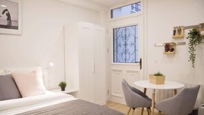 Un dormitorio con cama, mesita de noche y ventana con rejas decorativas.