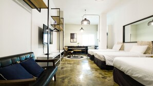 Une chambre d’hôtel moderne équipée d’un canapé, de deux lits, d’un bureau et d’un grand miroir.