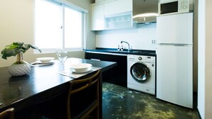 Une cuisine compacte équipée d’un lave-linge, d’un four à micro-ondes et d’un évier.