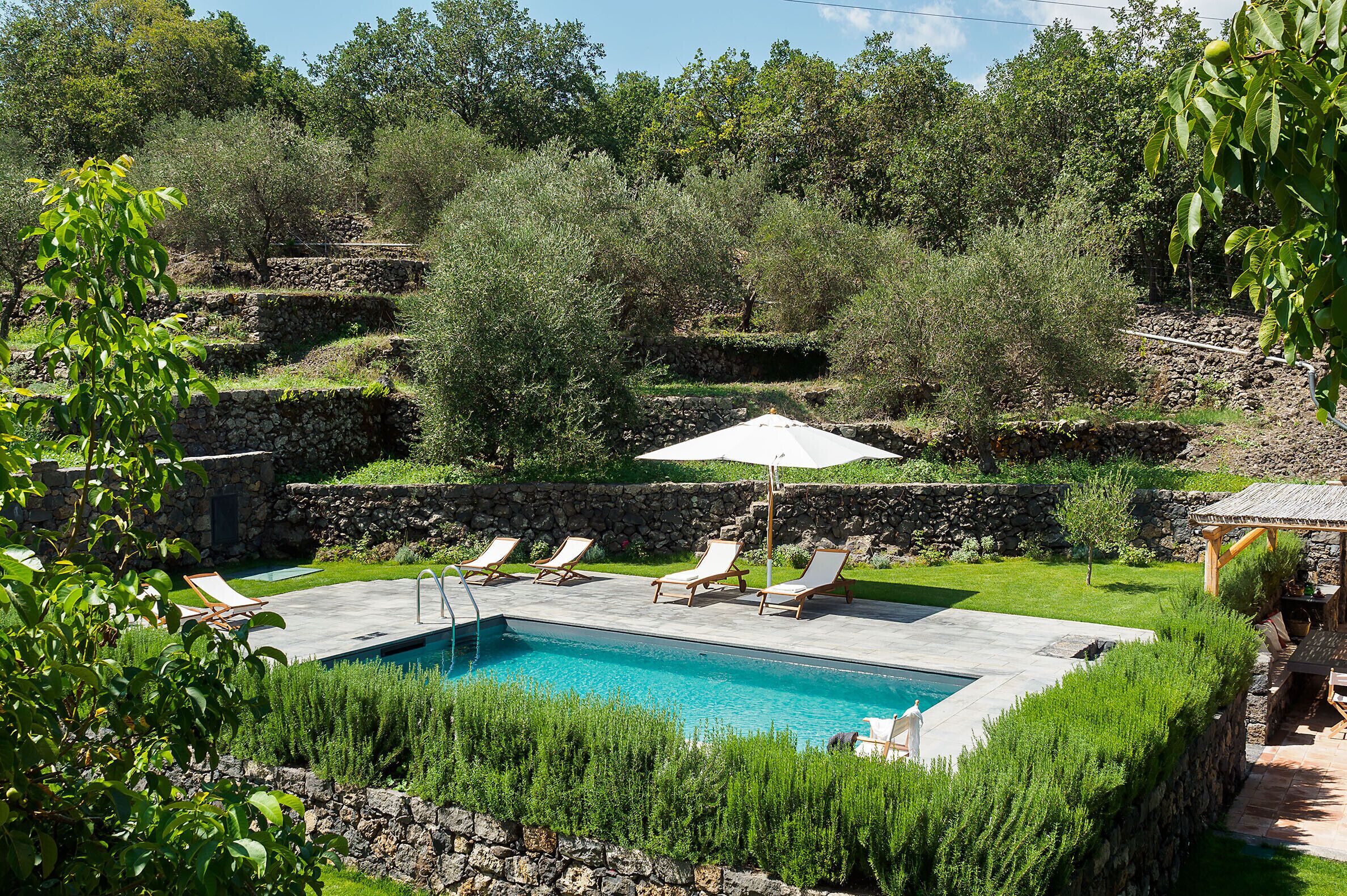 A swimming pool with lounge chairs and a stone wall.