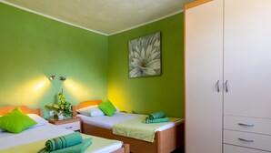 A hotel room with two beds, green walls, a large wardrobe, and a flower painting. - Rooms Edna - Twin Room (Dubrovnik)