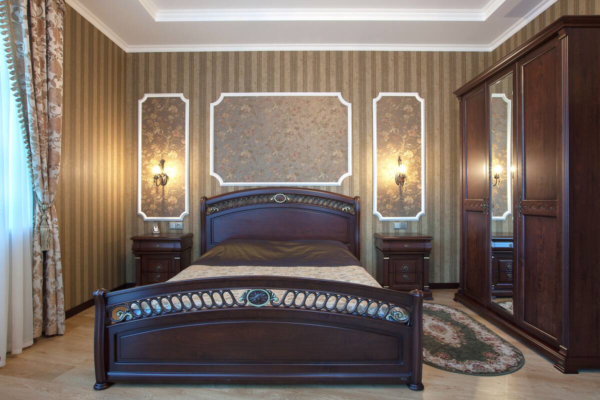 Une chambre à coucher avec un grand lit, deux tables de chevet avec des lampes, une armoire et un miroir.