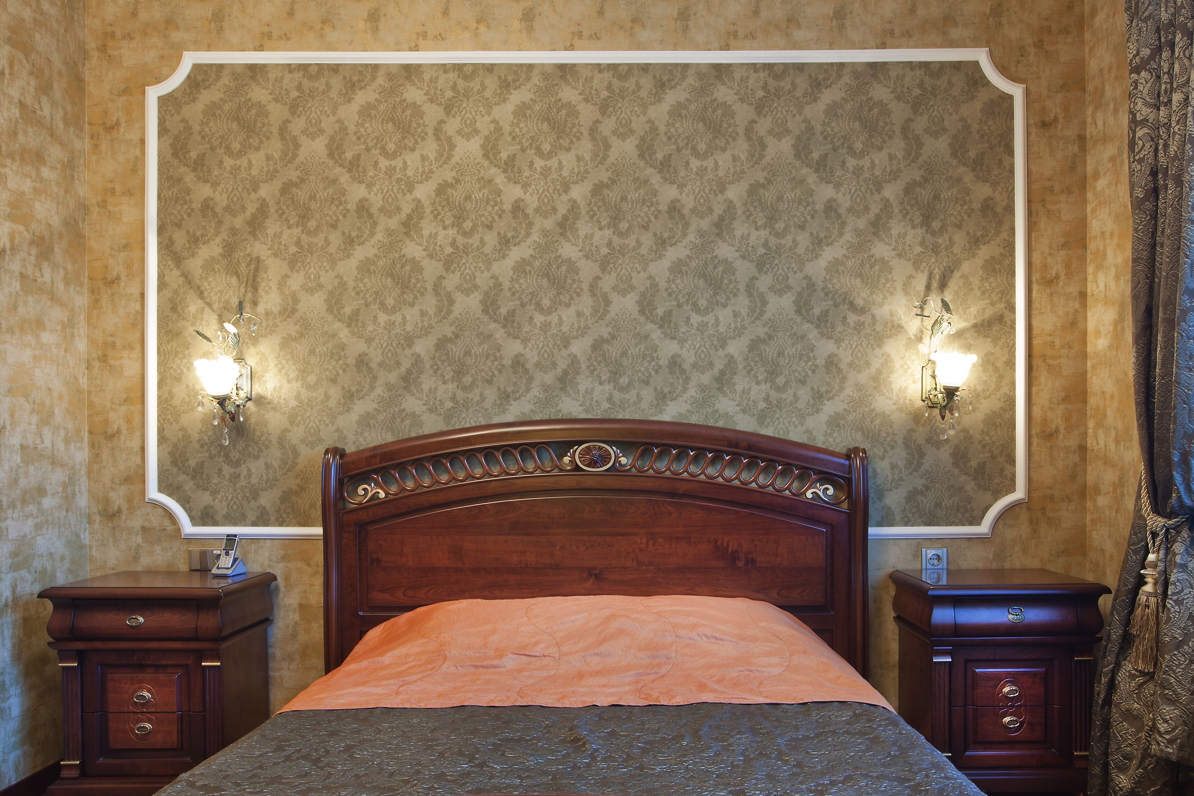 Een slaapkamer met een groot bed, twee nachtkastjes en een spiegel boven het bed.