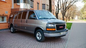 A GMC van parked in front of a building with a brick facade and large windows. - Hotel Helicopter (Kremenchuk)
