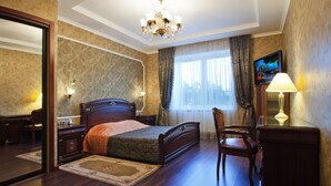 A hotel room with a large bed, a desk, a chair, a TV, and a chandelier. - Hotel Helicopter (Kremenchuk)