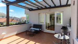 A balcony with a wooden pergola, a sofa, a small table, and a chair. - Apartment Alma - Two Bedroom Apartment with Terrace and Sea View (Dubrovnik)