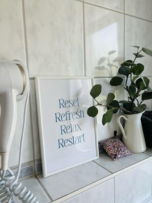 Een lijst met een bord waarop staat: 'Reset, Opfrissen, Ontspannen, Opnieuw beginnen' op een betegelde muur.