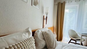 Een hotelkamer met een bed, bureau, stoel en een raam met gordijnen.