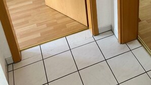 Een houten deur met het cijfer '3', die leidt naar een kamer met een houten vloer en een betegeld gebied.