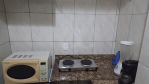 A kitchenette with a microwave, electric stove, and coffee maker. - APART MARCELO - STUDIO COPACABANA (RIO DE JANEIRO)