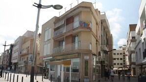 Un immeuble à plusieurs étages doté de balcons, d’un café et d’une promenade piétonne.