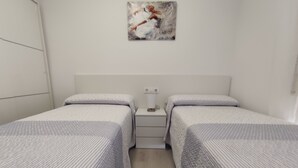 Une chambre avec deux lits simples, une table de chevet avec une lampe et un tableau au mur.