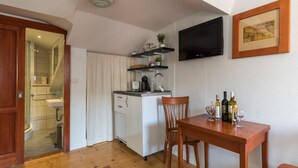 A compact kitchen with a sink, countertop, and a dining area with a table and chairs. - Apartments Ivana Old Town - Standard Studio - APT3 (Dubrovnik)