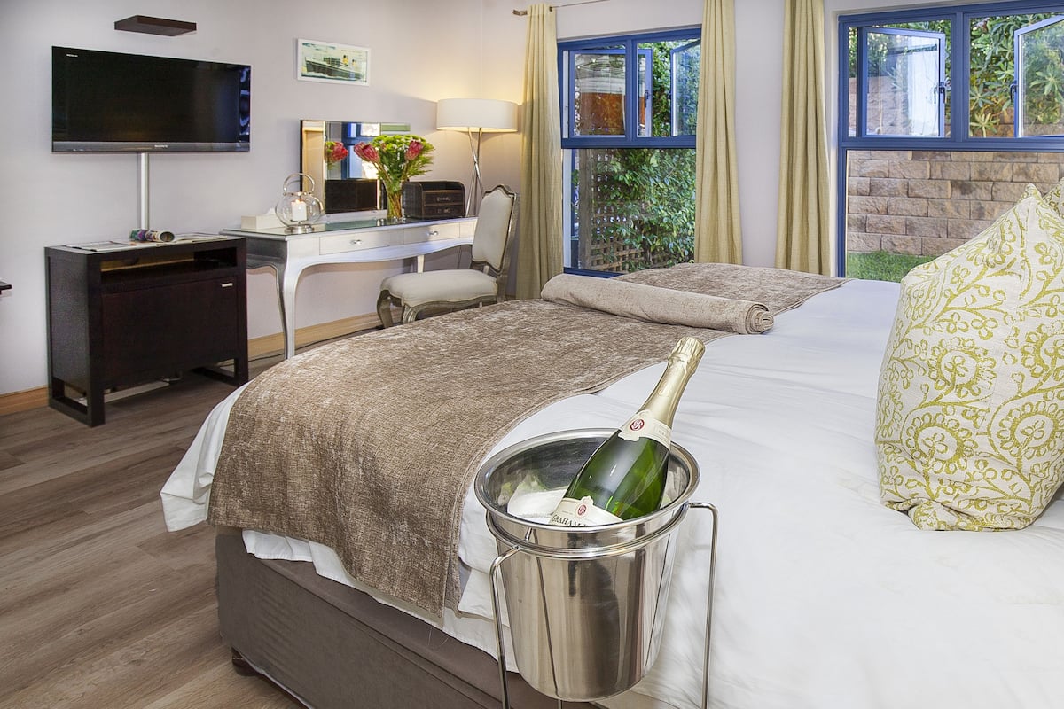Una habitación de hotel con cama, escritorio, televisor y ventana con cortinas.