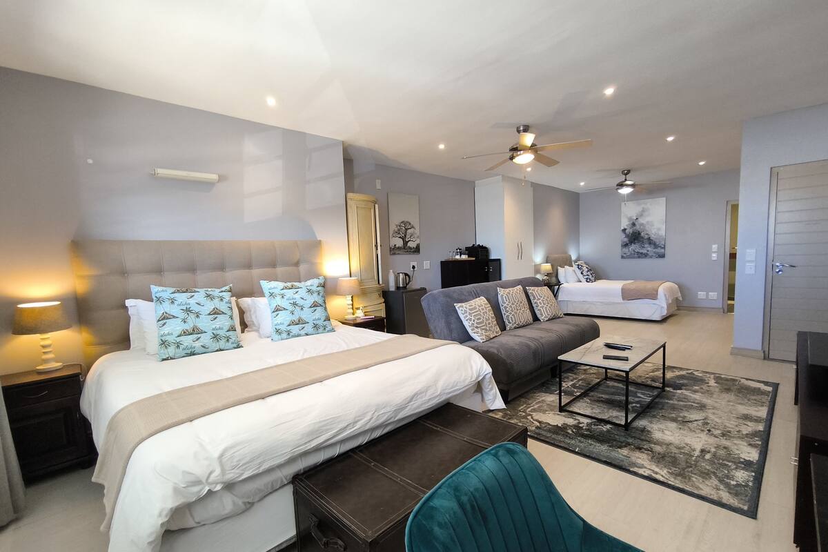 Una habitación de hotel moderna con una cama grande, un sofá, un escritorio y un ventilador de techo.