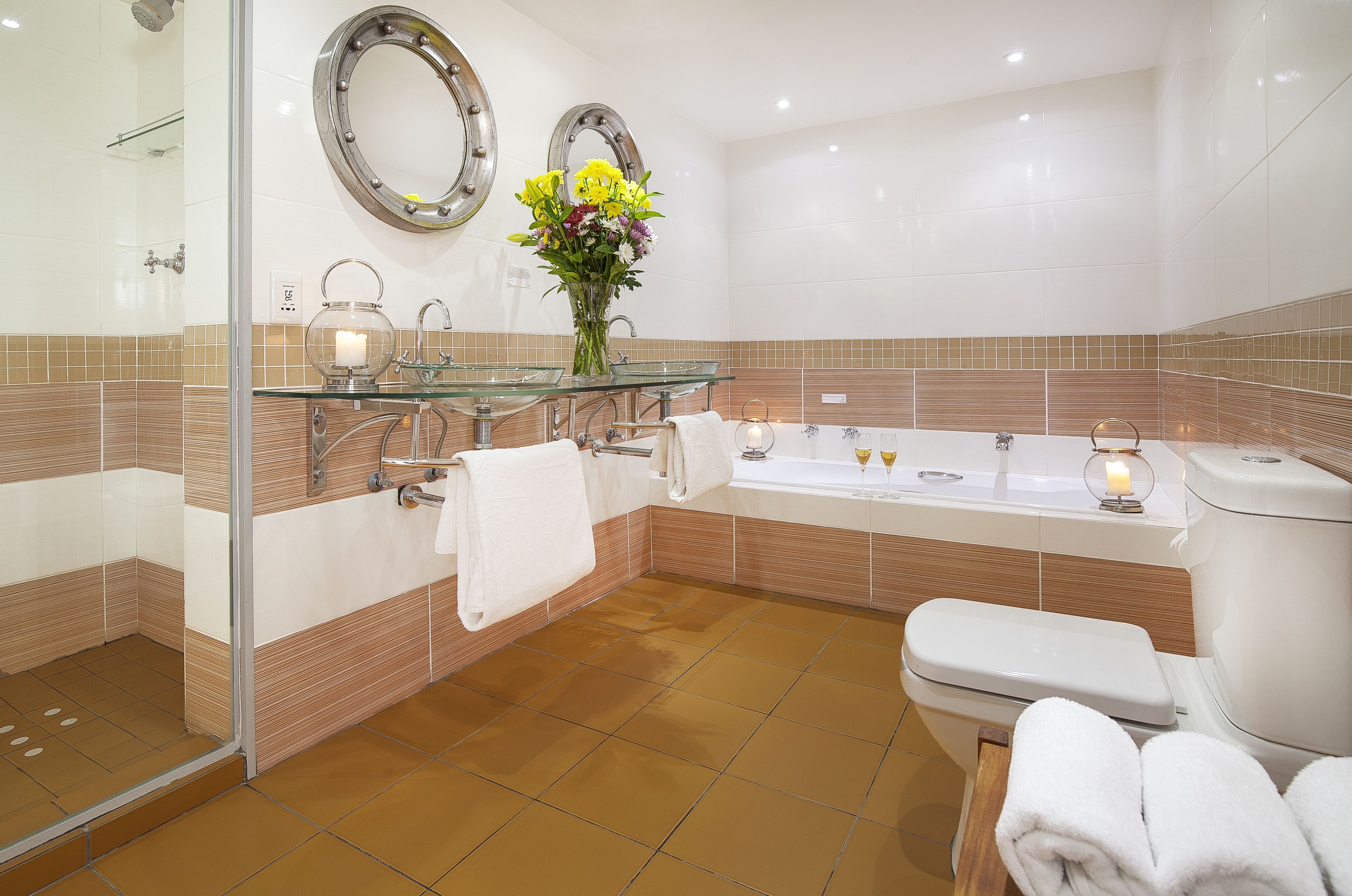 A modern bathroom with a glass shower enclosure, a large bathtub, and a toilet.