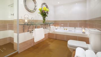A modern bathroom with a glass shower enclosure, a large bathtub, and a toilet.