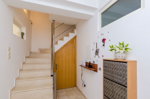 A staircase leading to a wooden door, a small shelf with a vase of flowers, and a wall-mounted decorative item. - Apartment Alba- Duplex Two Bedroom Apartment with Shared Pool and Sea View (Cavtat)