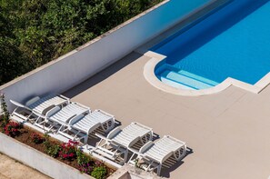 A swimming pool with white lounge chairs and a flower bed. - Apartment Alba- Duplex Two Bedroom Apartment with Shared Pool and Sea View (Cavtat)