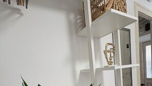 A modern interior with white shelving units, a decorative mask, and a large plant. - Apartments Noa Old Town - Studio - First Floor (Dubrovnik)