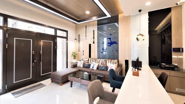 A modern living room with a sofa, coffee table, and chairs. There is a large window, a door, and a kitchen area visible. - Clear Sky Laurel B&B (Magong)