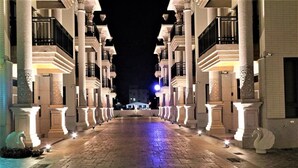 A nighttime view of a hotel corridor with evenly spaced columns and illuminated steps. - Clear Sky Laurel B&B (Magong)