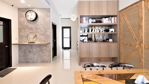 A modern interior with a wooden bookshelf, a round wall clock, and a dining area with chairs. - Clear Sky Laurel B&B (Magong)