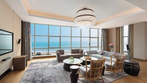 Amplia sala de estar con un gran ventanal con vistas a la playa, un candelabro y un moderno conjunto de sofás.