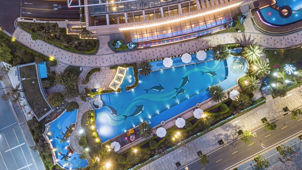 Vista aérea de un hotel con piscina, jardines ajardinados y una estructura de edificio moderna.