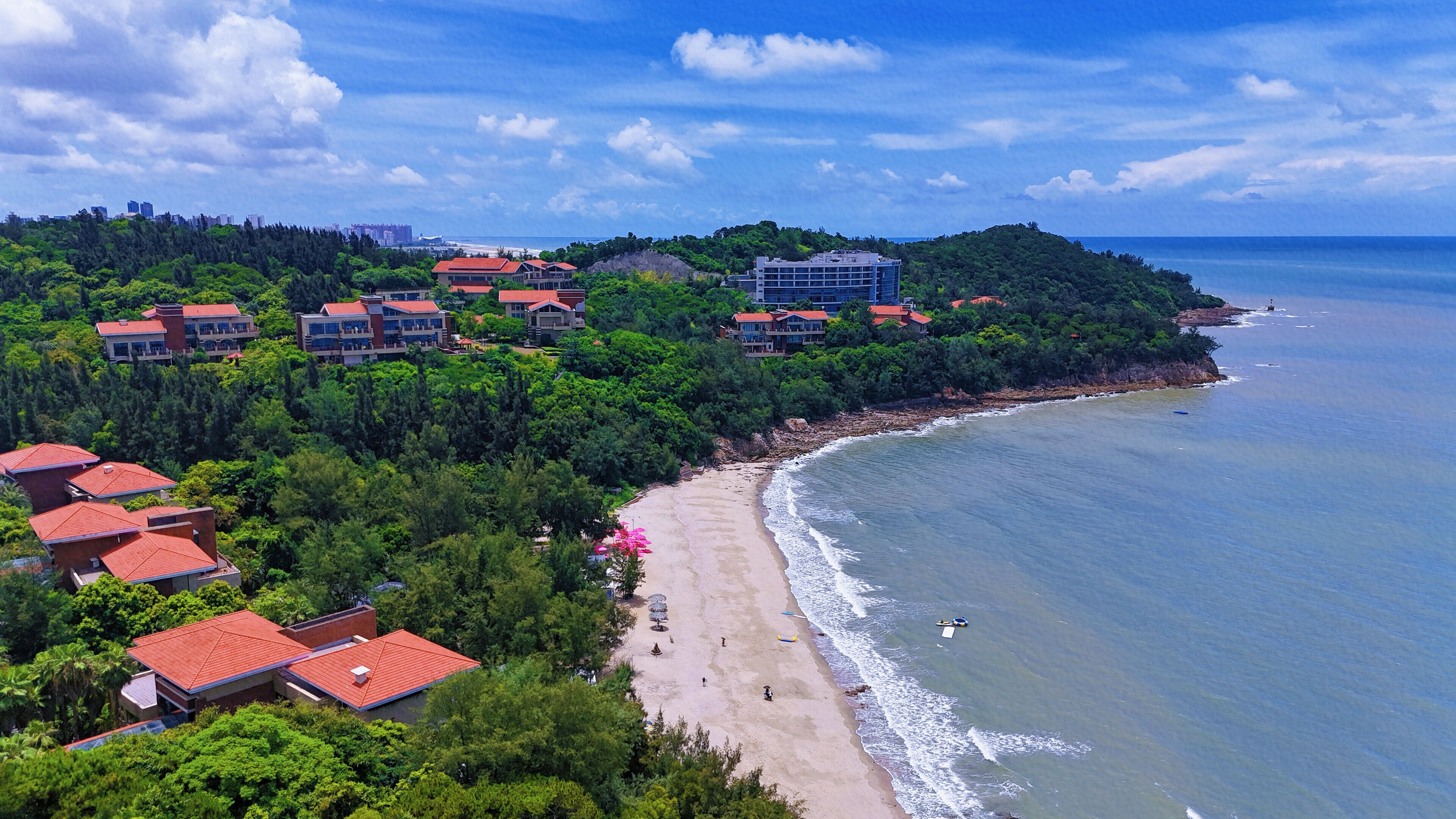 A coastal resort with multiple buildings, a sandy beach, and a view of the ocean.
