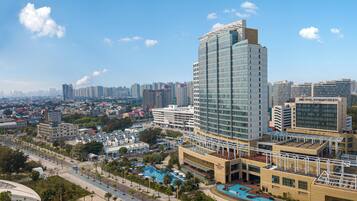 A modern hotel with a large glass facade, a swimming pool, and a landscaped courtyard.