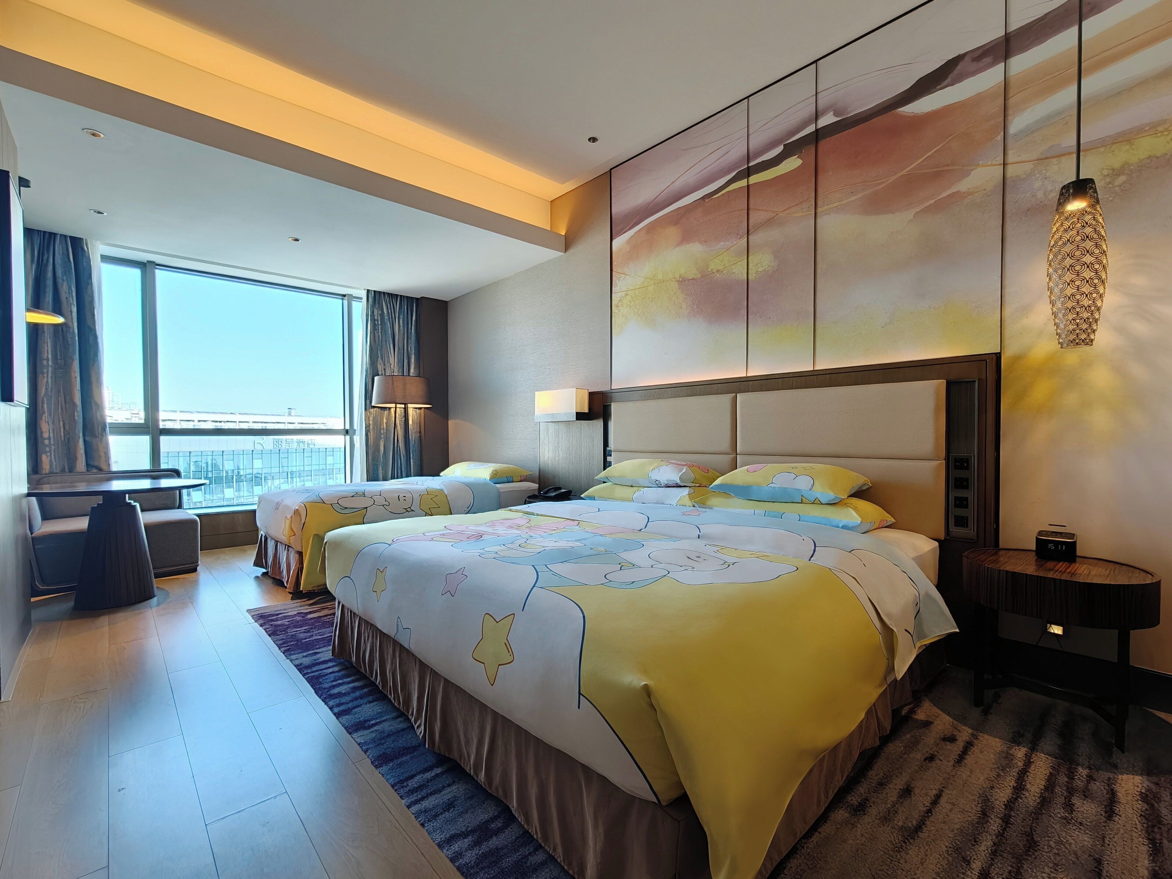 A modern hotel room with a large bed, a desk, and a view of the city.