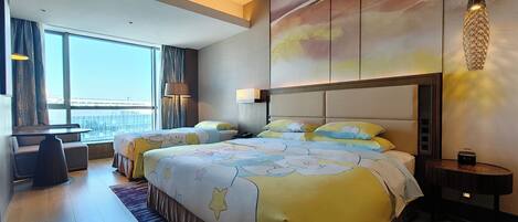 A modern hotel room with a large bed, a desk, and a view of the city.