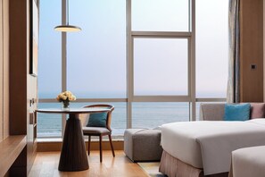 Una habitación de hotel con un ventanal grande, una mesa de comedor con sillas, un sofá y una cama.