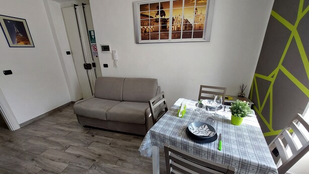 Un coin repas avec une table dressée pour deux personnes, un canapé et une vue sur la ville.