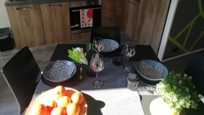 Une table à manger dressée avec des assiettes, des bols, des verres et un saladier rempli d’oranges.