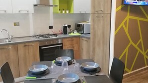 Une cuisine moderne avec des meubles blancs et verts, un four à micro-ondes et un téléviseur fixé au mur.