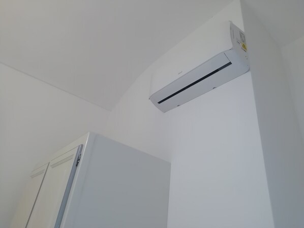A white air conditioning unit mounted on a wall in a room with a white door.