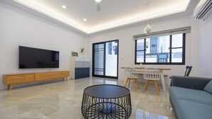 A modern living room with a flat-screen TV, a round black coffee table, a sofa, and a dining area with chairs. - Sun Day B&B (Magong)
