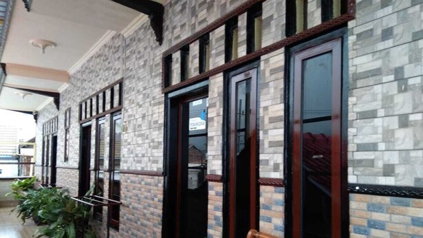 A hallway with tiled walls, wooden-framed windows, and potted plants. - Balqis Home Stay (Ngadisari)