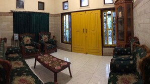 A room with a sofa set, a wooden coffee table, and a yellow door. - Balqis Home Stay (Ngadisari)