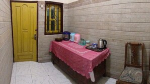 A narrow hallway with a yellow door, a table with a pink tablecloth, and two wooden chairs. - Balqis Home Stay (Ngadisari)
