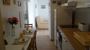 Une cuisine compacte comprenant un coin repas, un réfrigérateur, un grille-pain et une table à manger, cette dernière étant dressée avec des assiettes et un verre de jus d'orange.