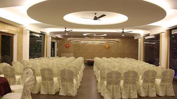 A conference room with rows of chairs, ceiling fans, and a decorative light fixture.